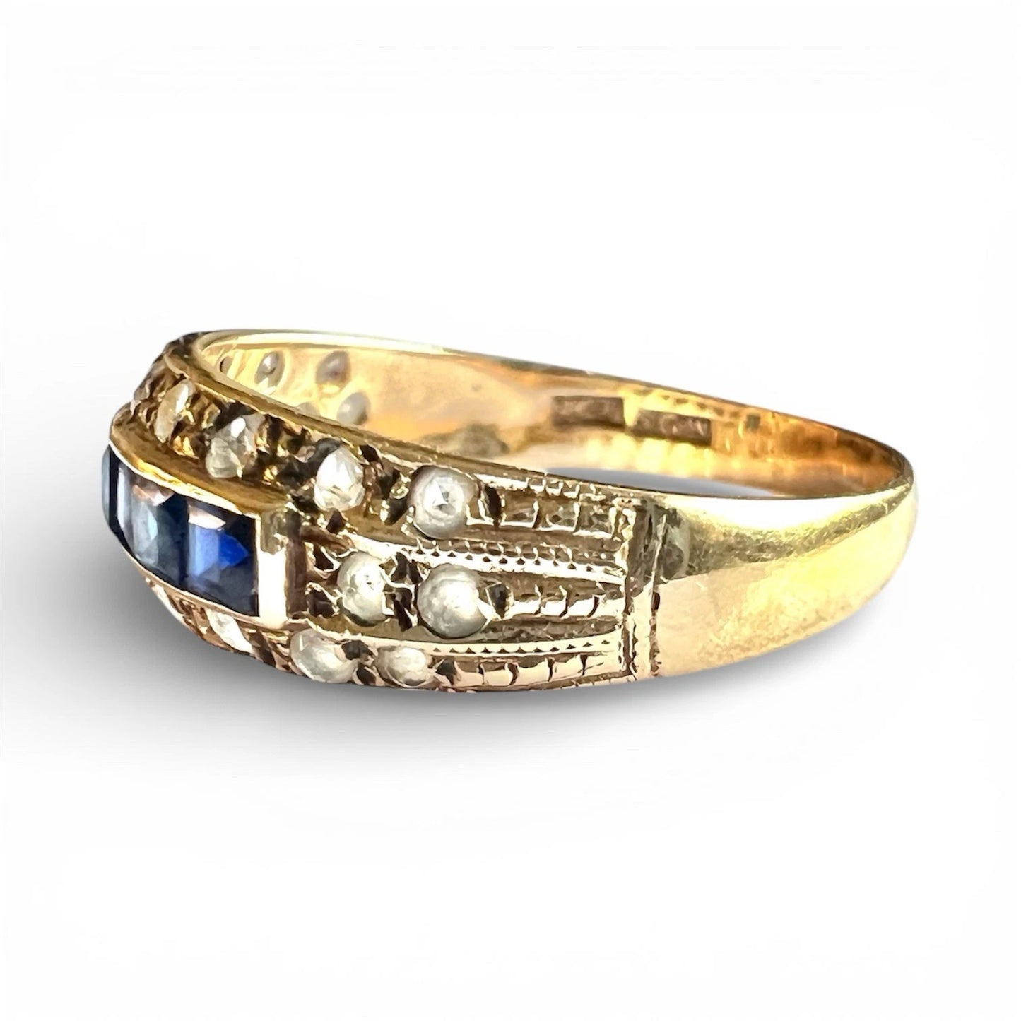 Gold ring with a blue sapphire gemstones and cubic zirconia with textured detail on a white background