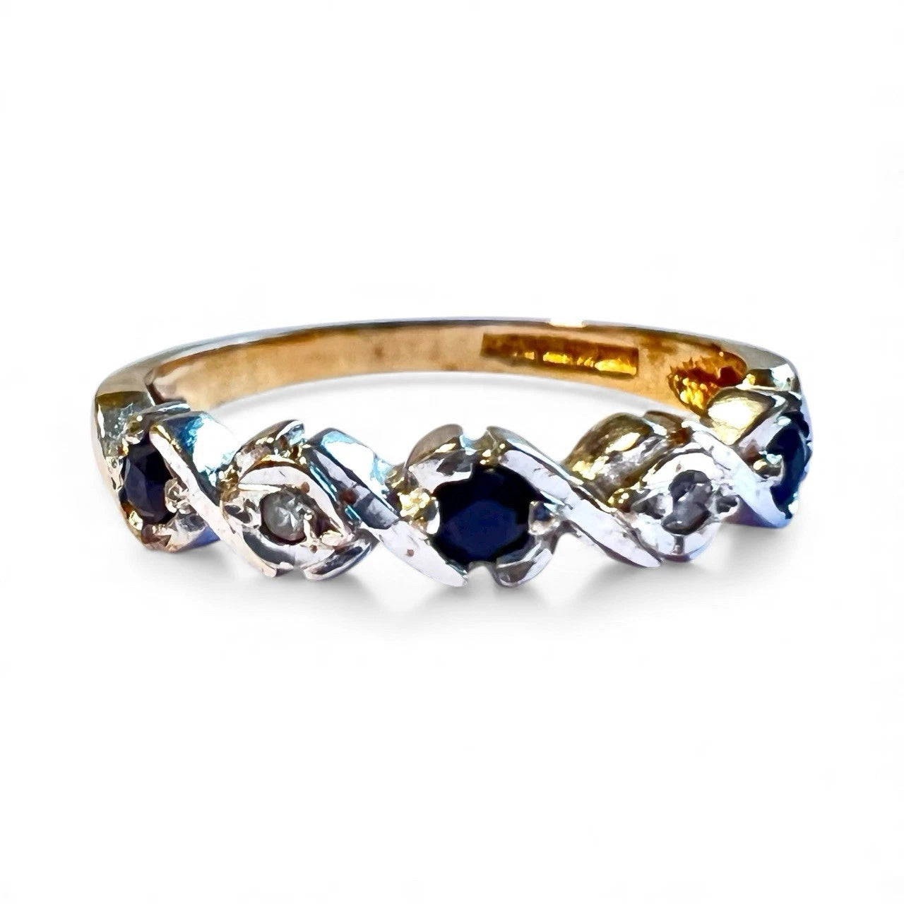 Gold ring with blue sapphire gemstones and diamonds on a white background. Close up view 
