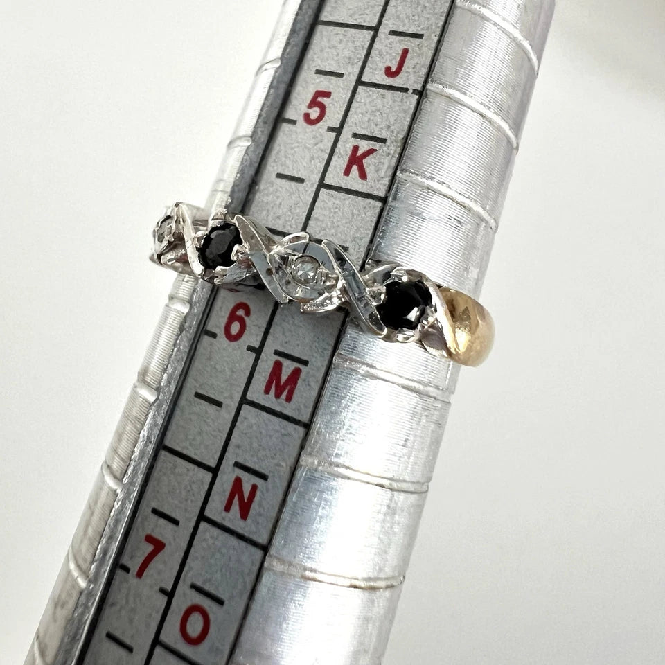 ring with gemstones on a metal ring sizer for size reference.