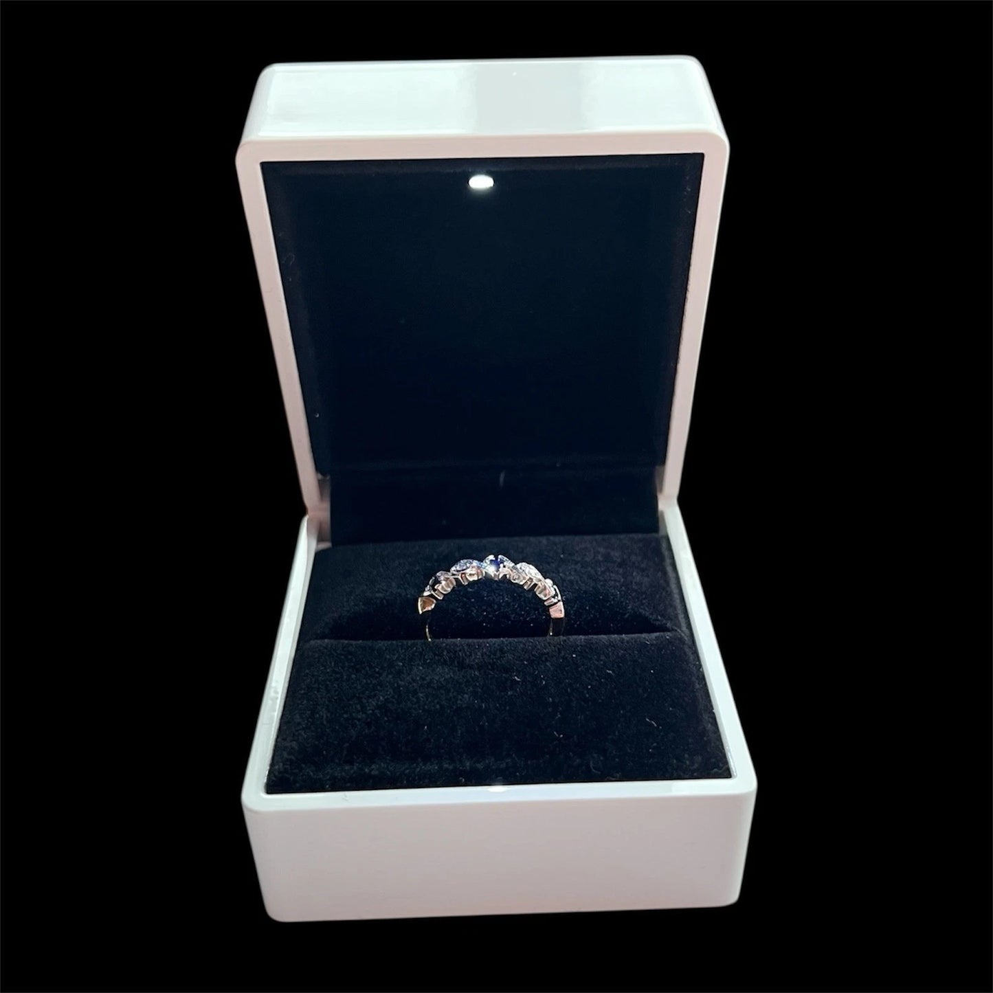 Sapphire and diamond ring in an open jewellery box on a black background