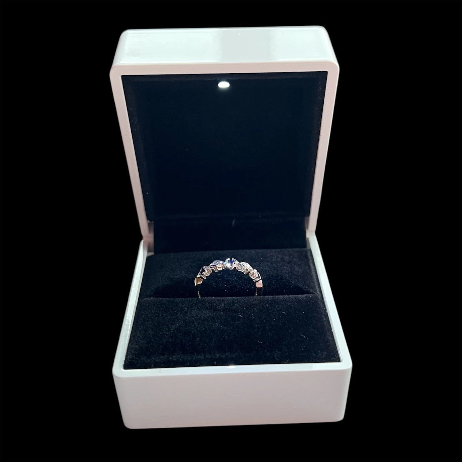 Sapphire and diamond ring in an open jewellery box on a black background