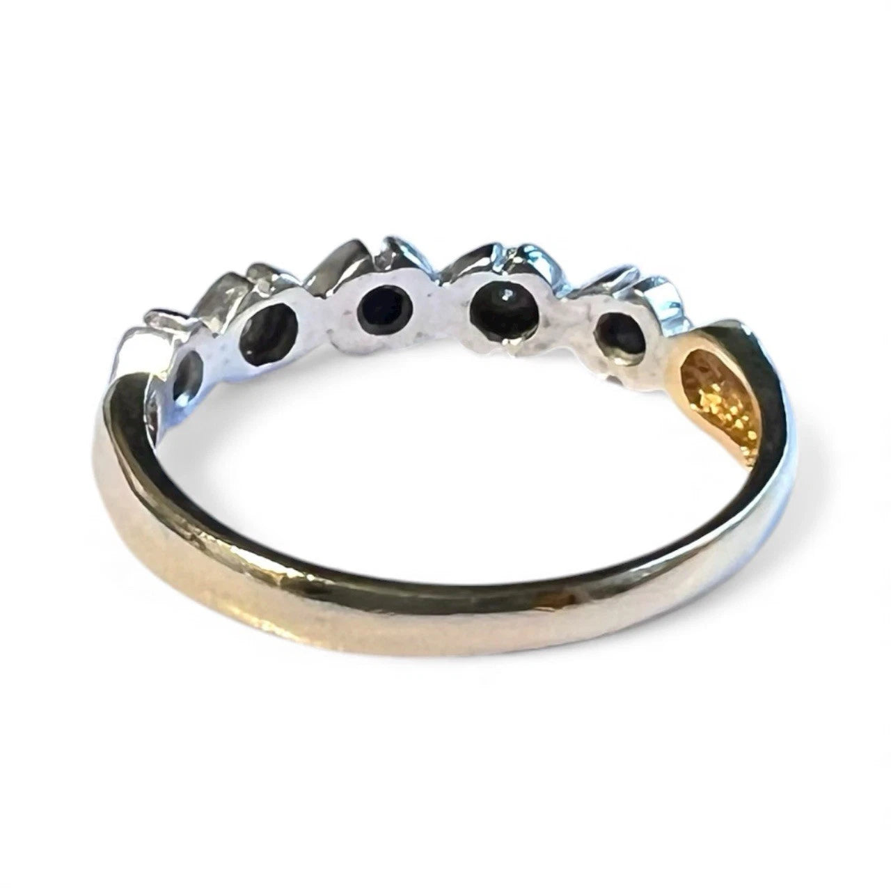 Gold ring with sapphire and diamond gemstones on a white background. Close up rear view of setting and gold band. 