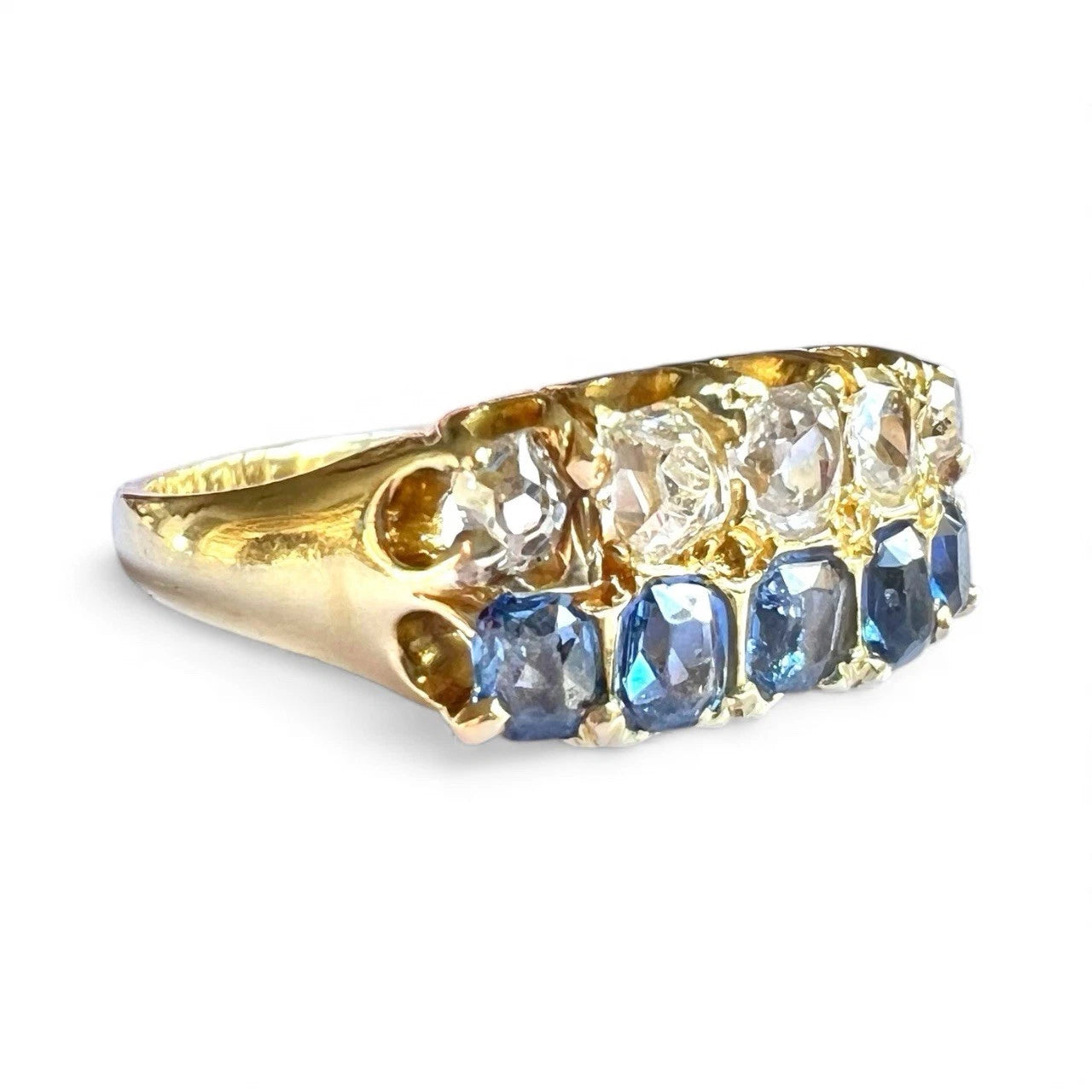 Gold ring with diamonds and blue sapphire gemstones on a white background