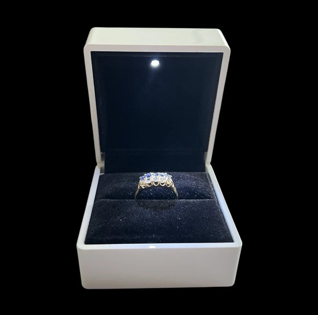 Gold sapphire and diamond ring in a white box with a black interior