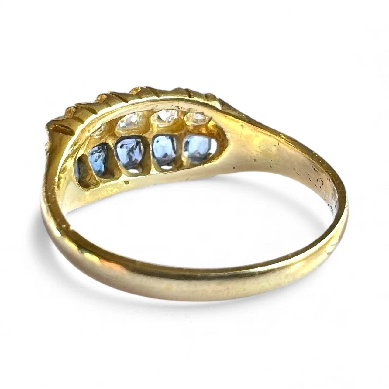 Gold ring with sapphire and diamonds on a white background. Close up rear view of setting and gold band 