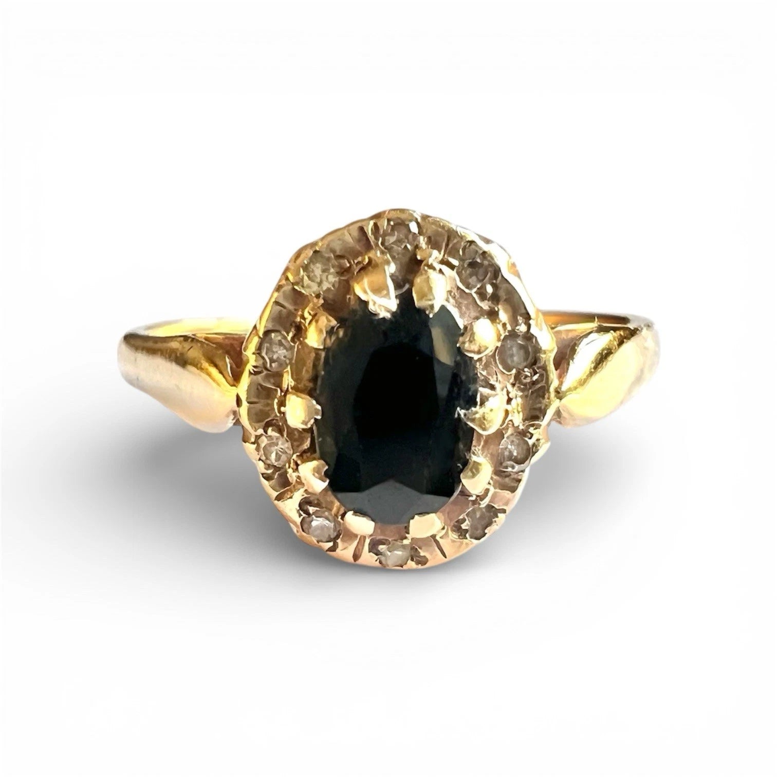 Gold ring with a sapphire gemstone and diamond halo on a white background
