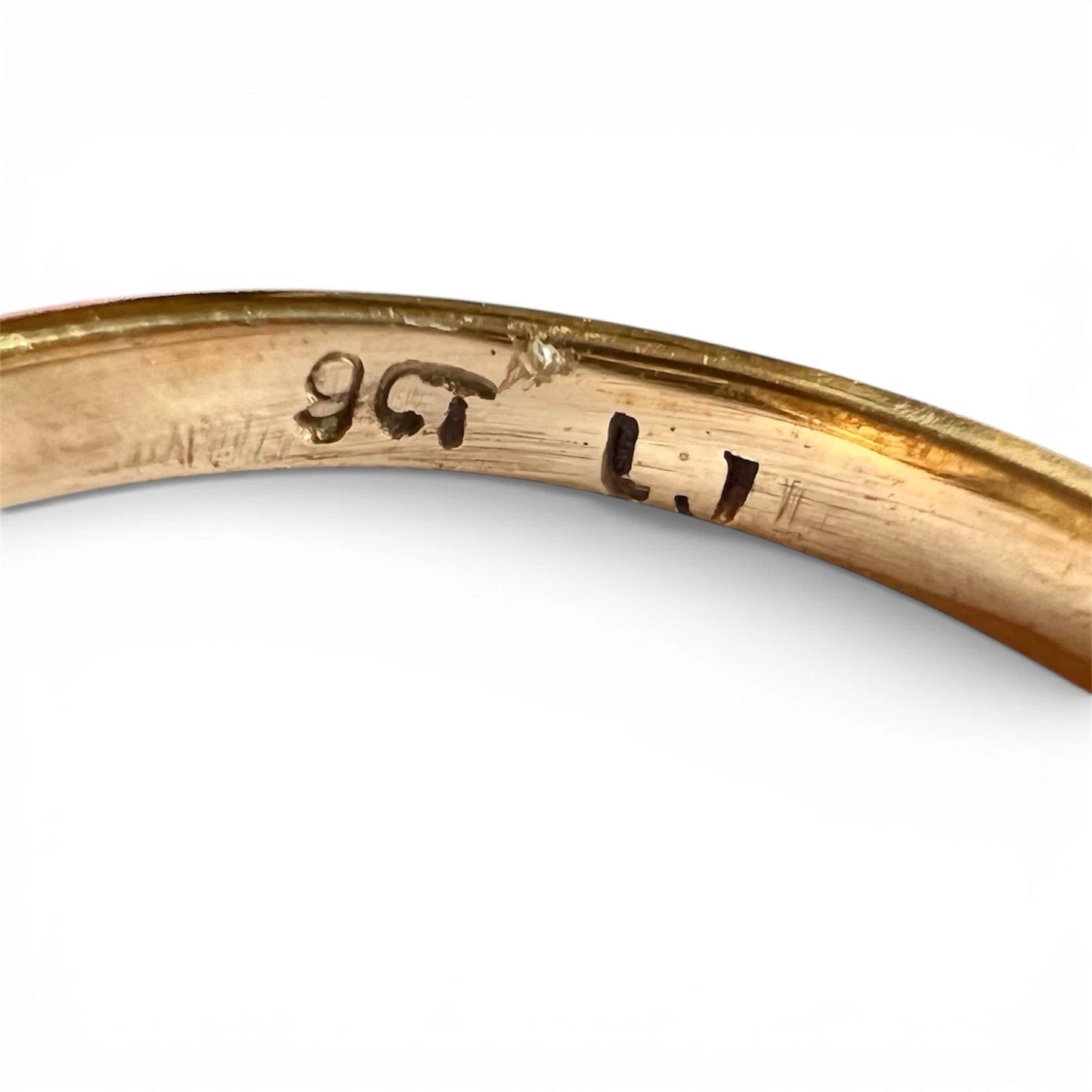 Close-up of a gold ring with engraved 9ct hallmark on a white background