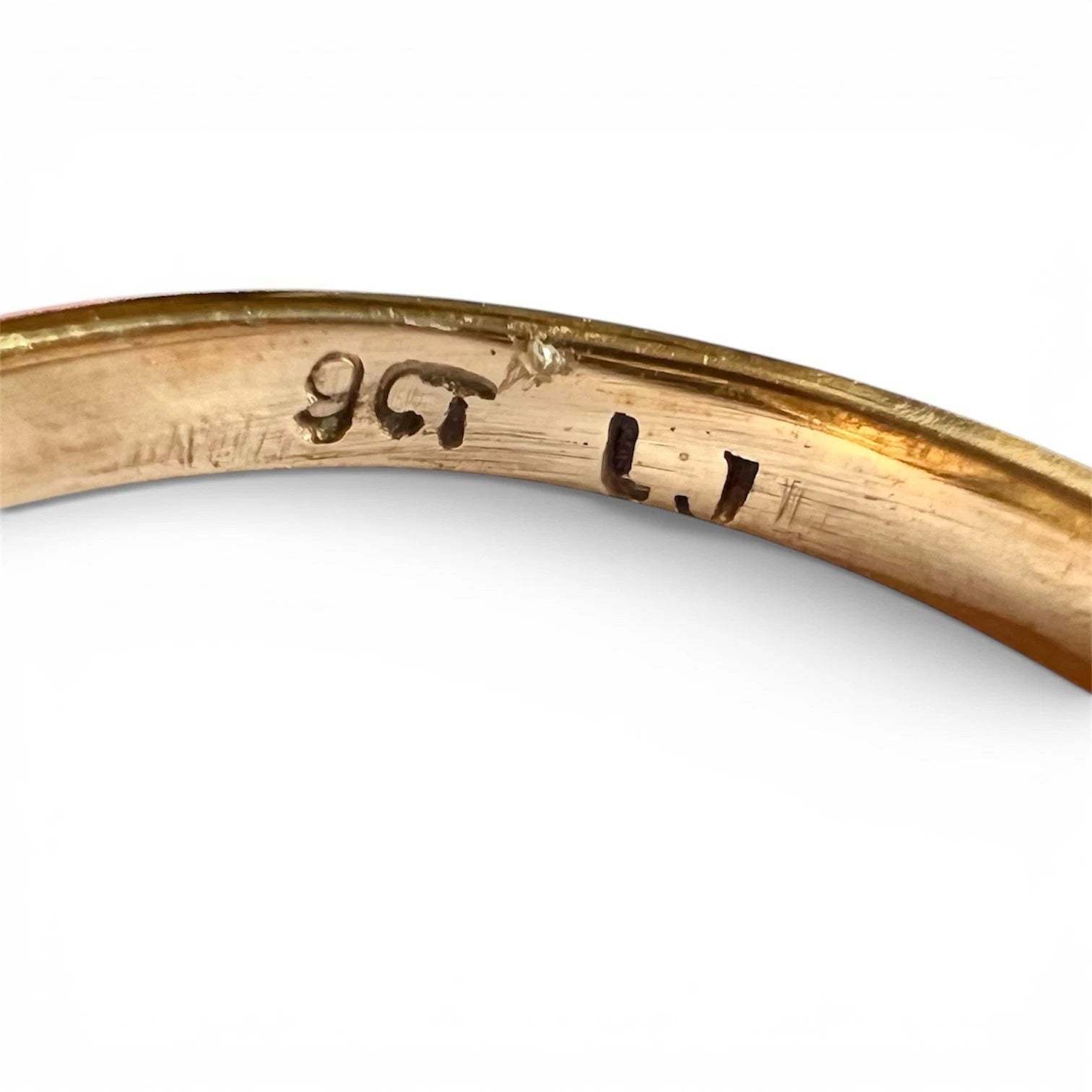 Close-up of a gold ring with engraved 9ct hallmark on a white background