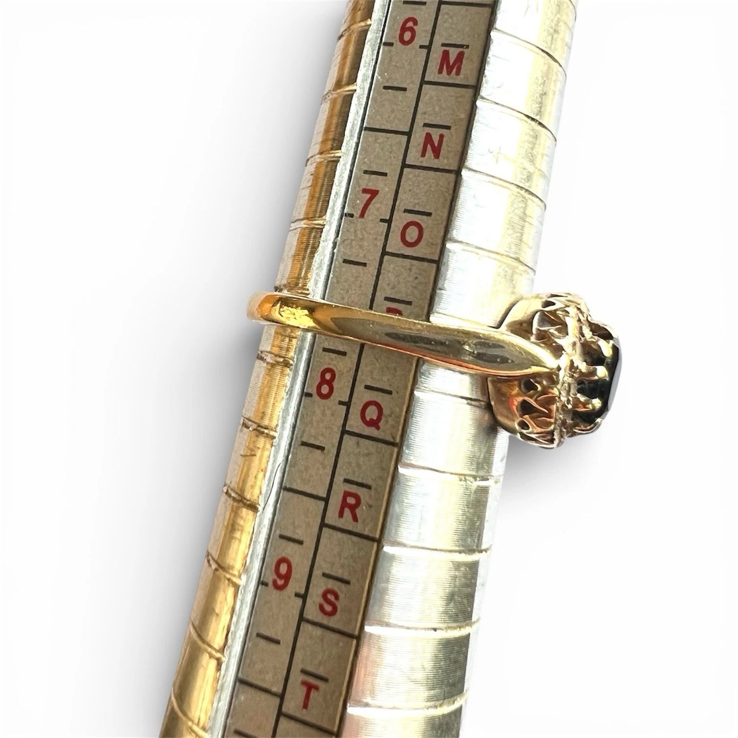 Gold ring on a ring sizer with a white background