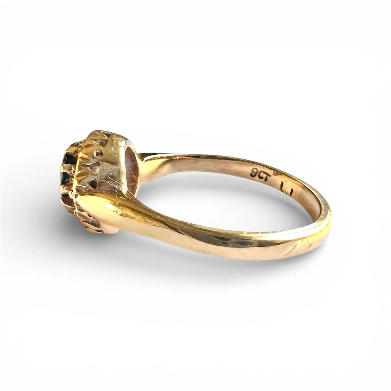 Gold ring with a oval cut sapphire and diamond halo on a white background
