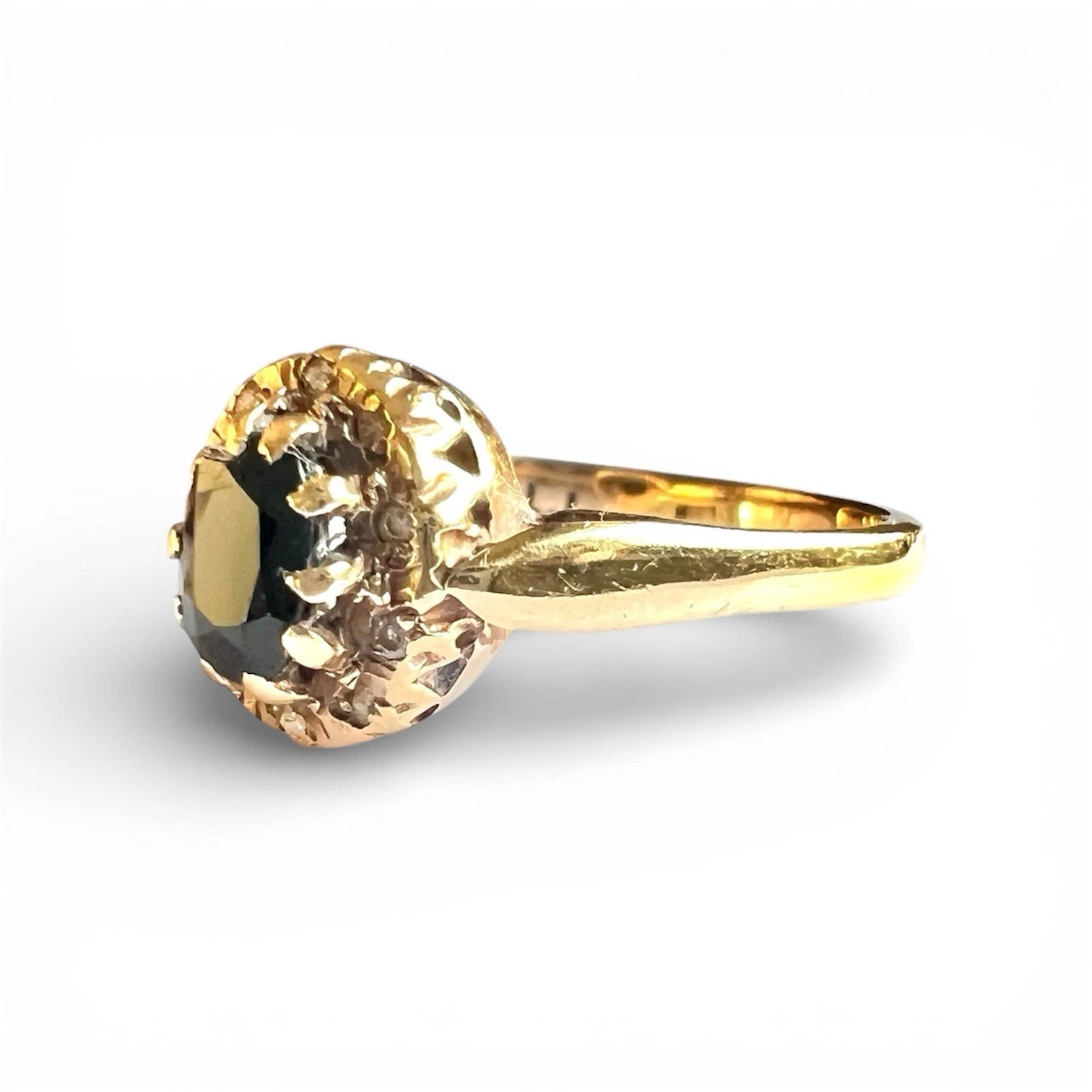 Gold ring with a oval cut sapphire and diamond surround on a white background