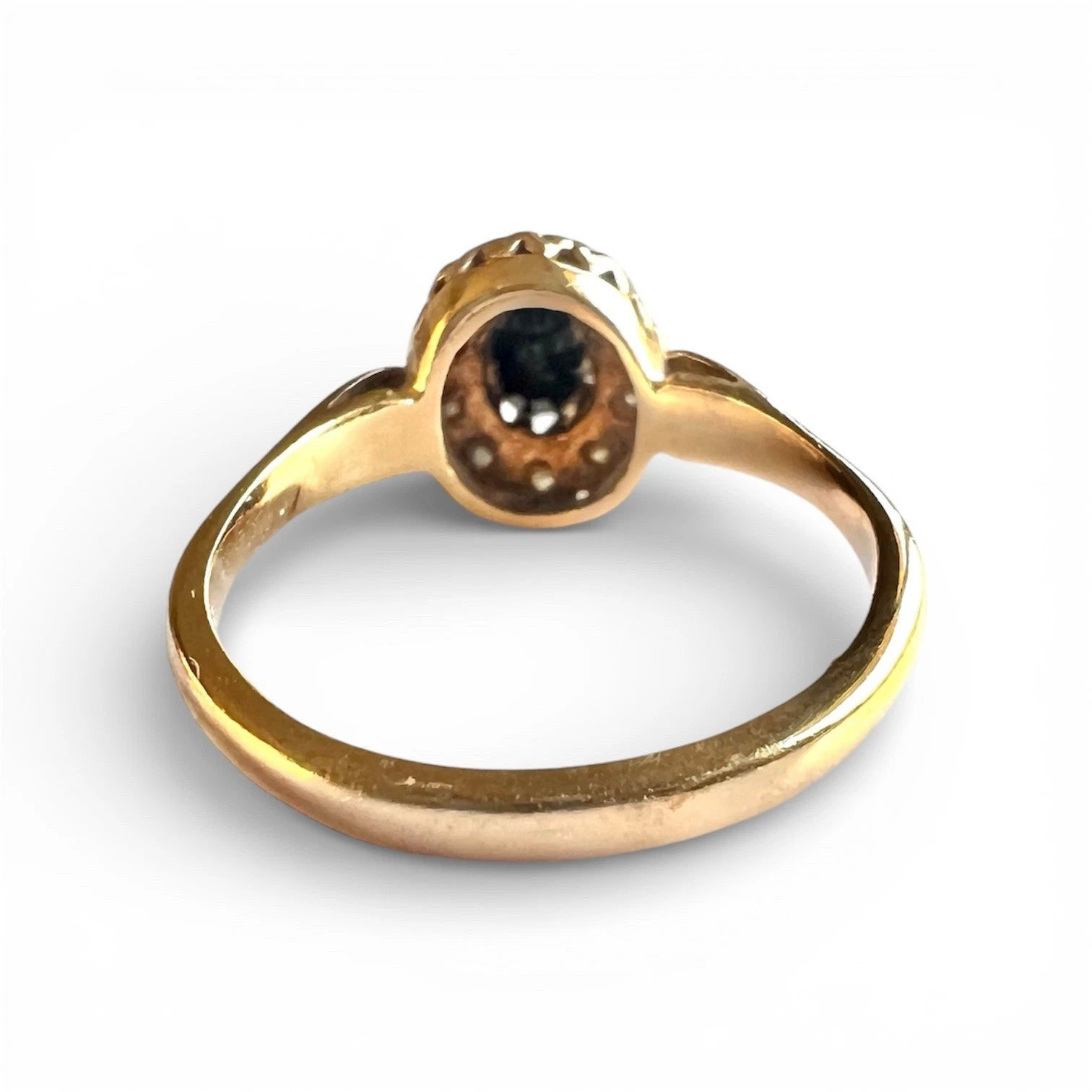 Rear view gold ring with a sapphire gemstone on a white background