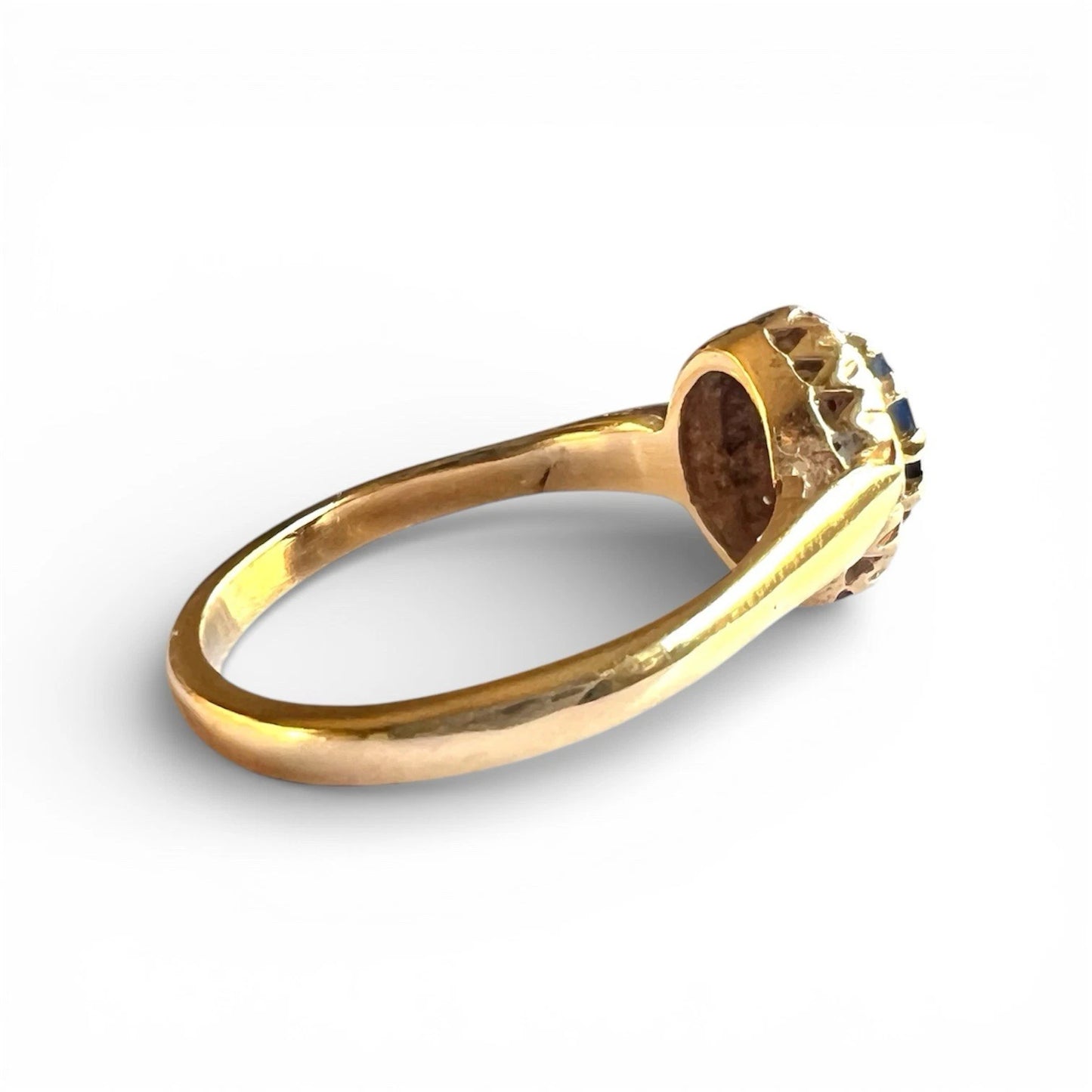 Side view gold ring with a sapphire and diamond halo on a white background