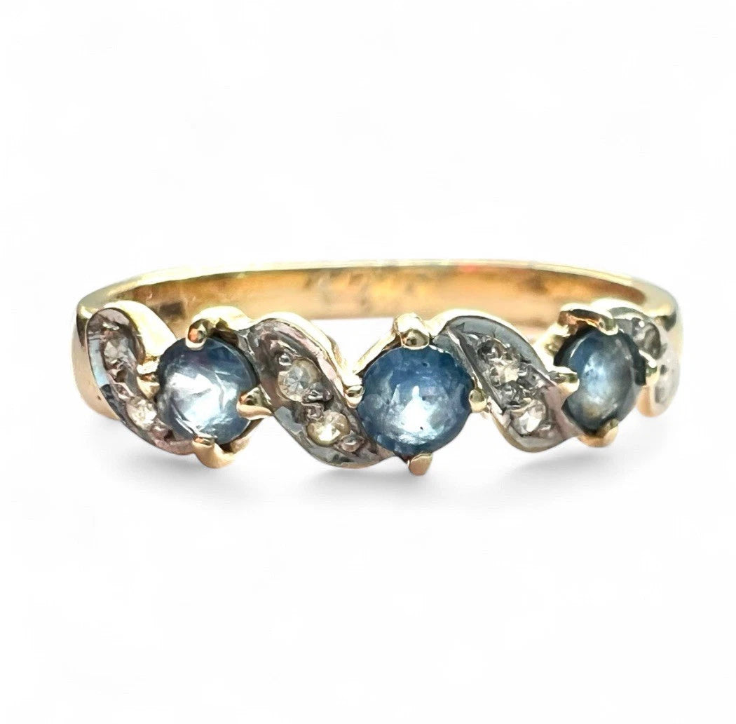 Gold ring with blue sapphire gemstones and diamonds on a white background. Close up front view 
