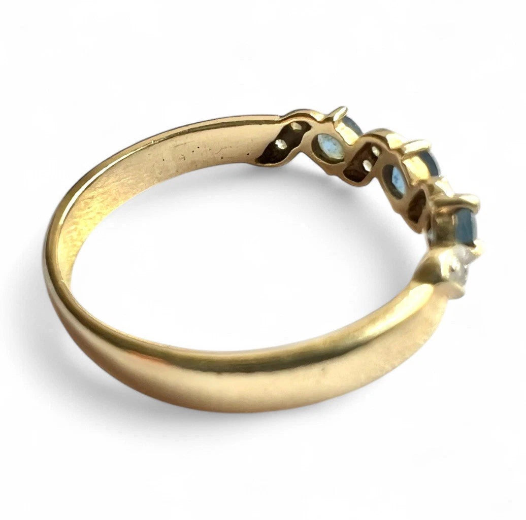 Gold ring with sapphire gemstones on a white background. Close up side view. 