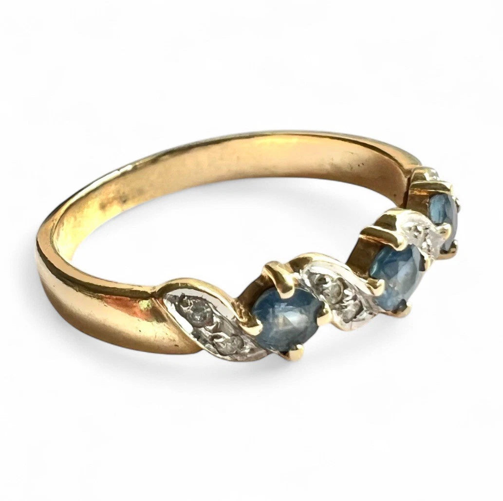 Gold ring with light blue sapphire gemstones and diamonds on a white background