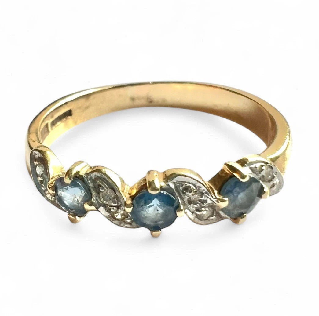 Gold ring with blue sapphire gemstones and diamonds on a white background