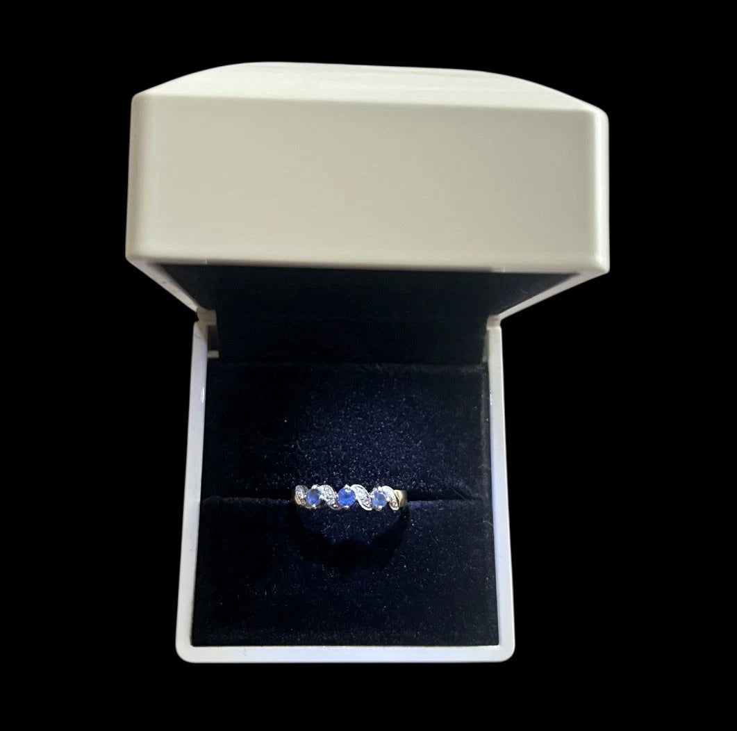 Ring with blue sapphire stones in an open jewellery box on a black background