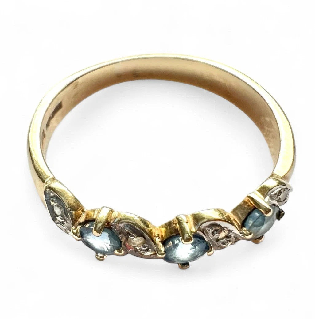 Gold ring with blue sapphire gemstones and diamond on a white background