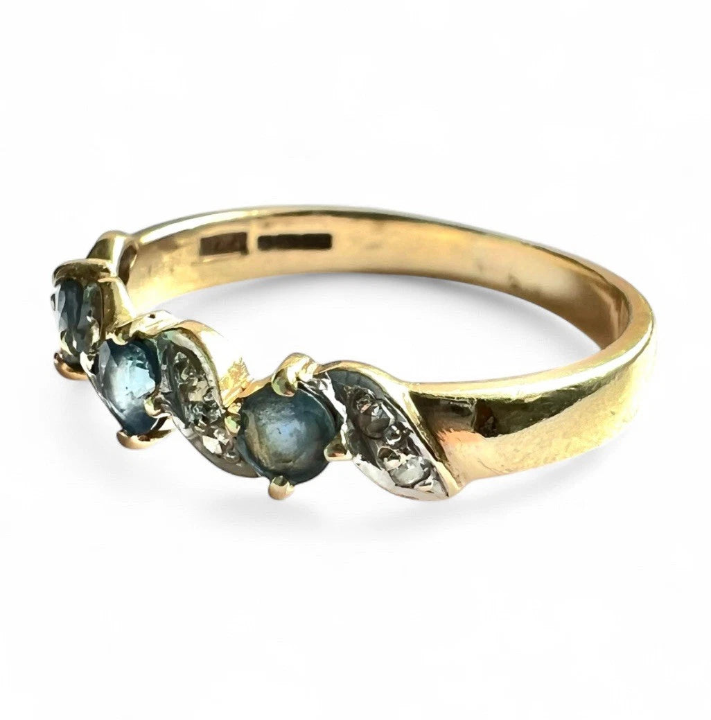 Gold ring with light blue sapphire gemstones and diamonds on a white background