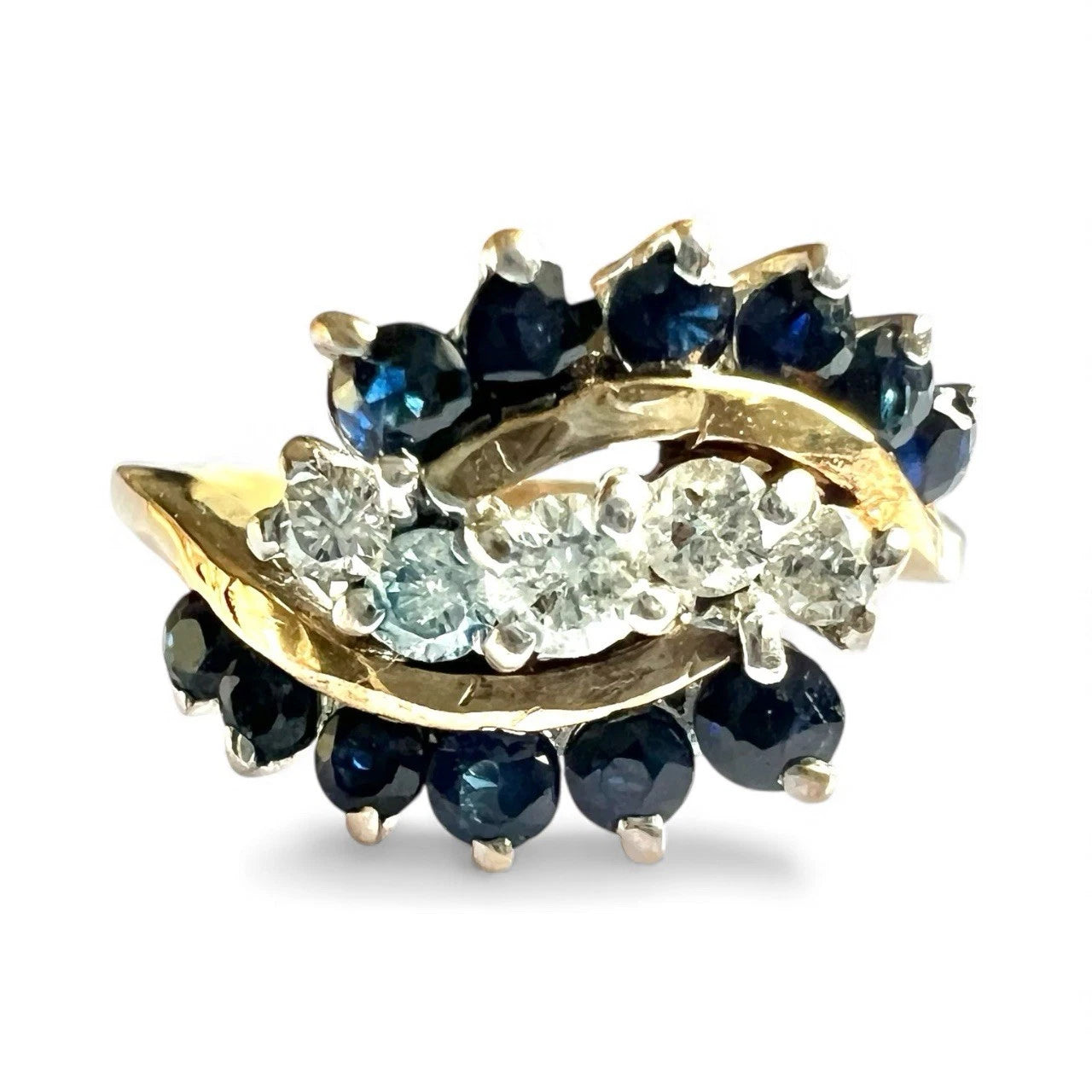 Gold ring with blue sapphire gemstones and diamonds on a white background close from view of setting 