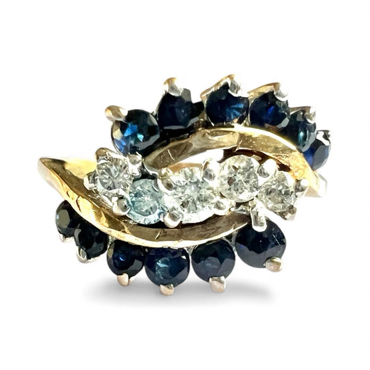 Gold ring with blue sapphire gemstones and diamonds on a white background close from view of setting 