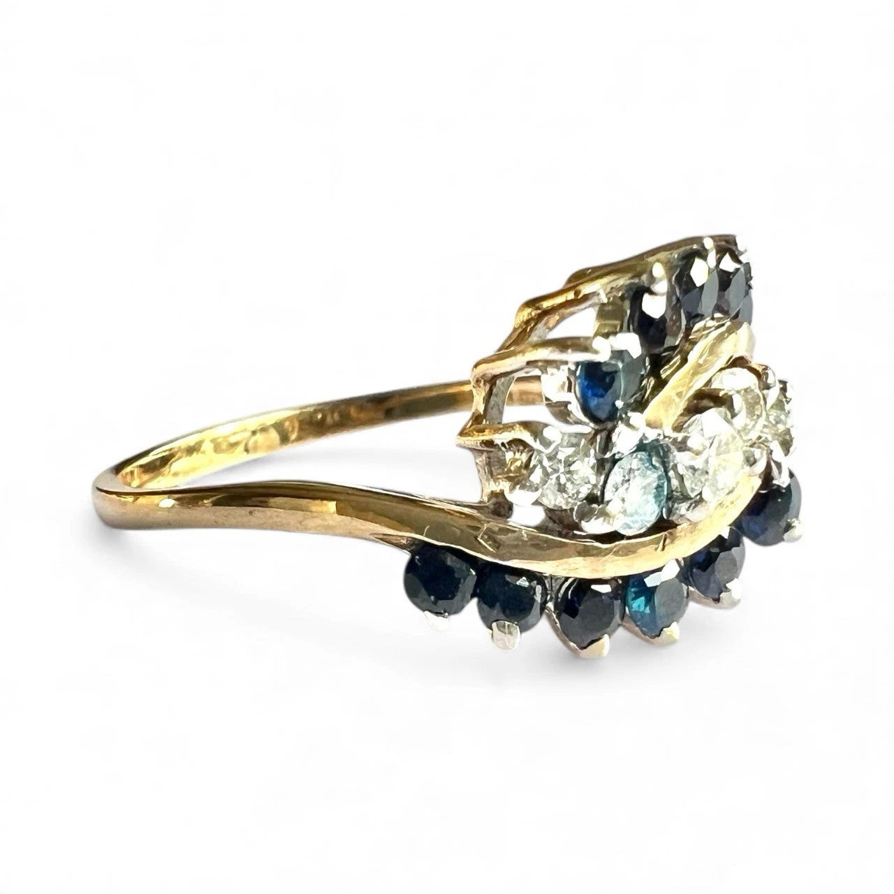 Gold ring with blue sapphire gemstones and diamonds on a white background