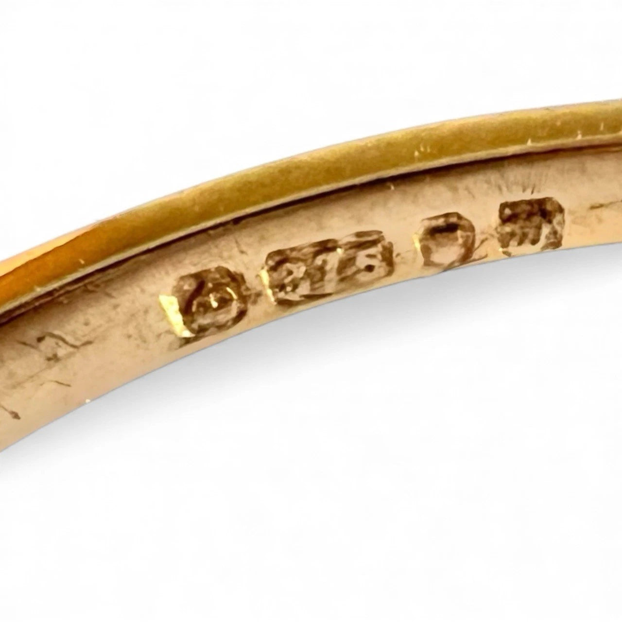 Close-up of a gold ring with engraved hallmark on a white background