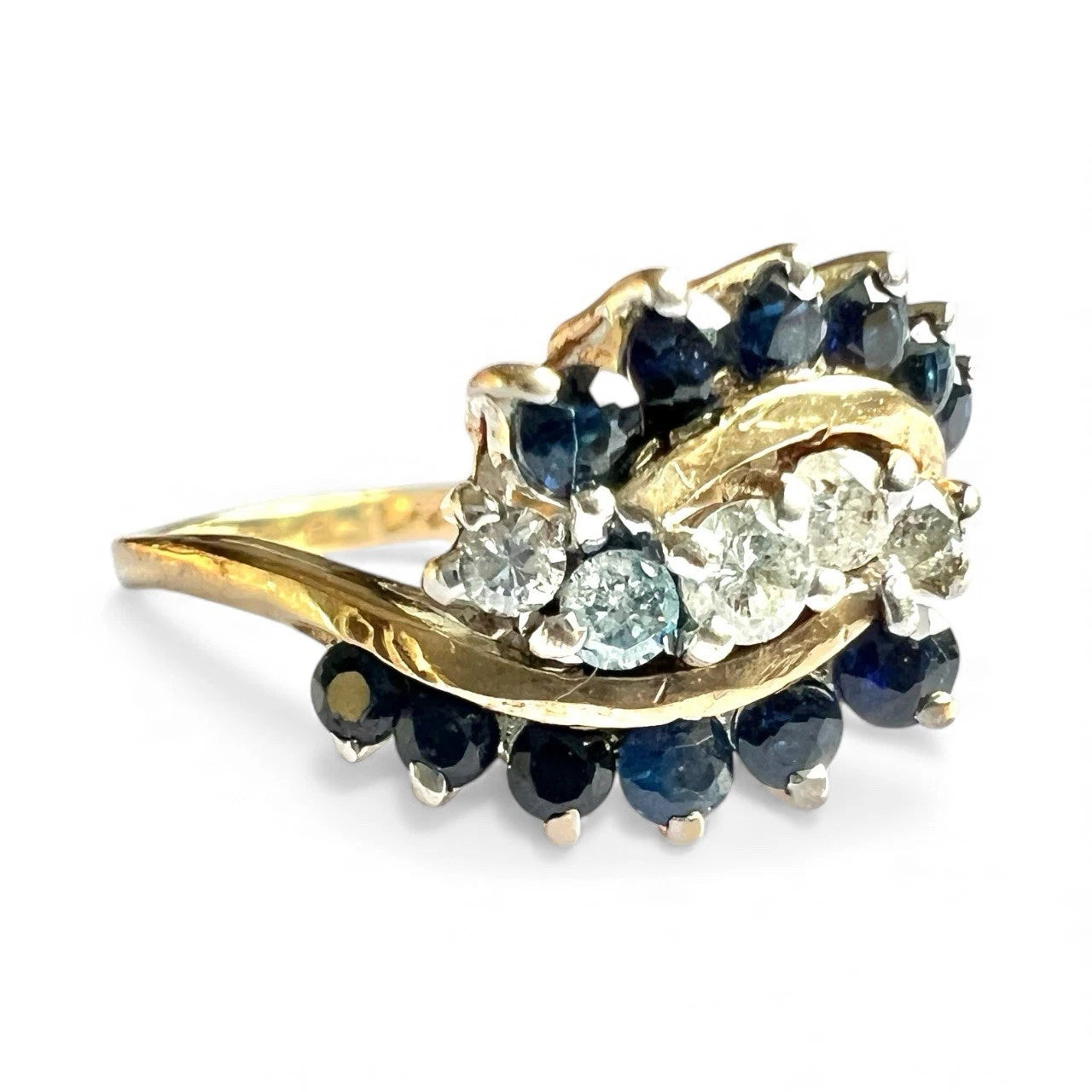 Gold ring with blue sapphire gemstones and diamonds on a white background