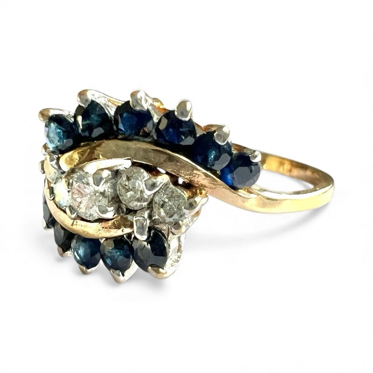 Gold ring with blue sapphire gemstones and diamonds on a white background