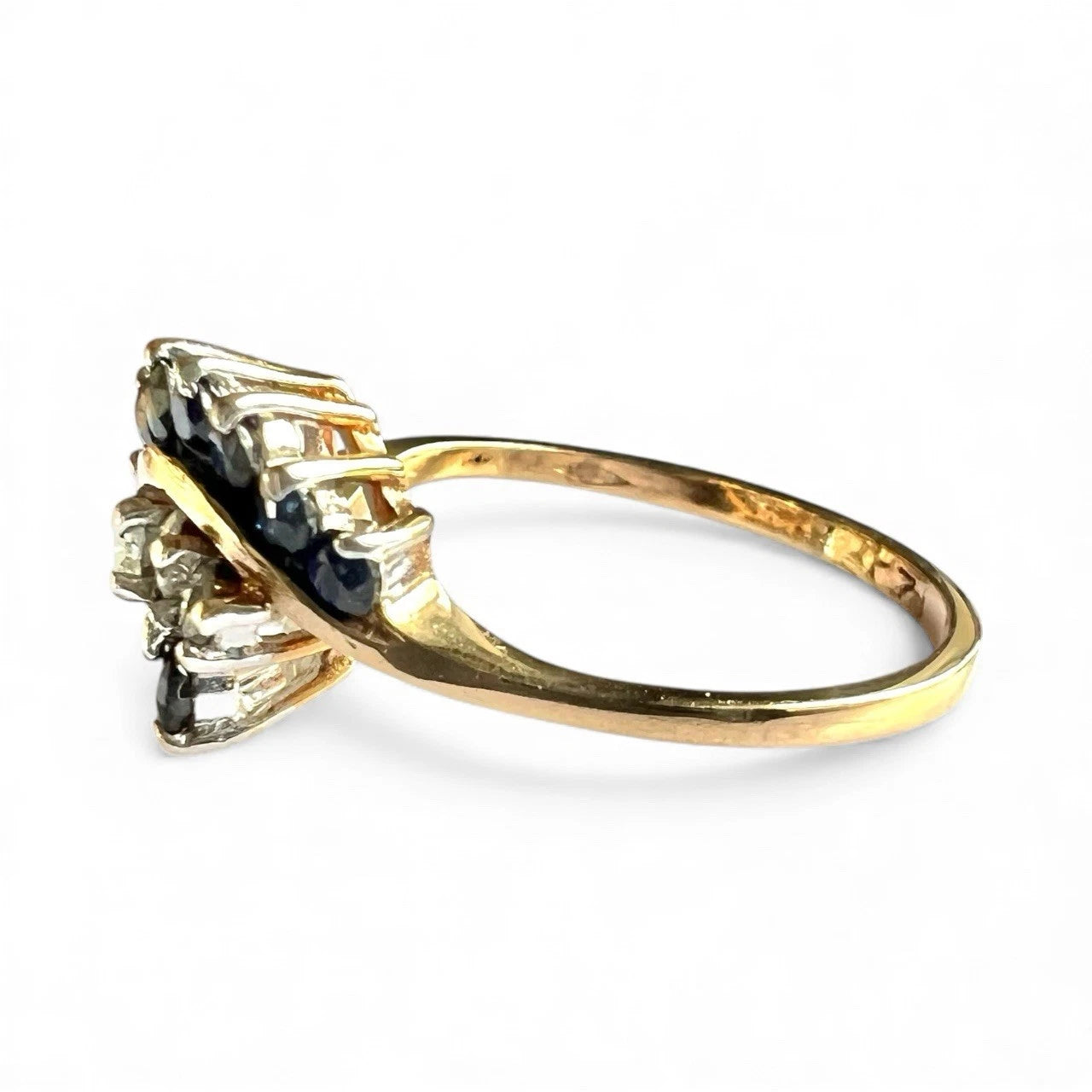 Gold ring with blue sapphire and diamonds on a white background close up side view 