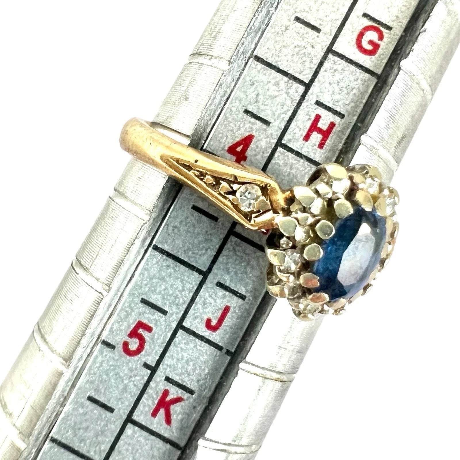 Gold ring with a blue gemstone on a ring sizer for size reference