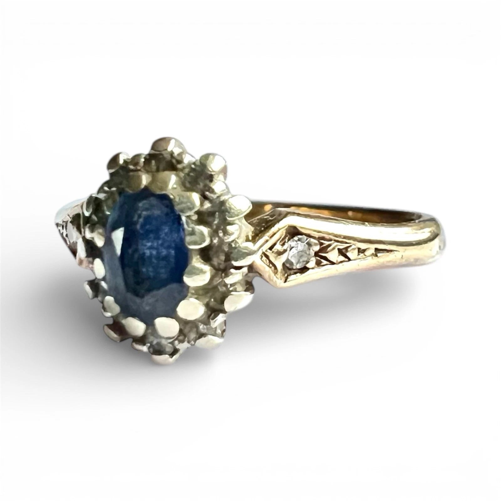 Gold ring with a blue sapphire gemstone and diamond accents on a white background