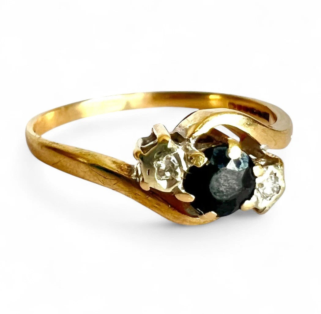 Gold ring with a sapphire gemstone and diamond on a white background