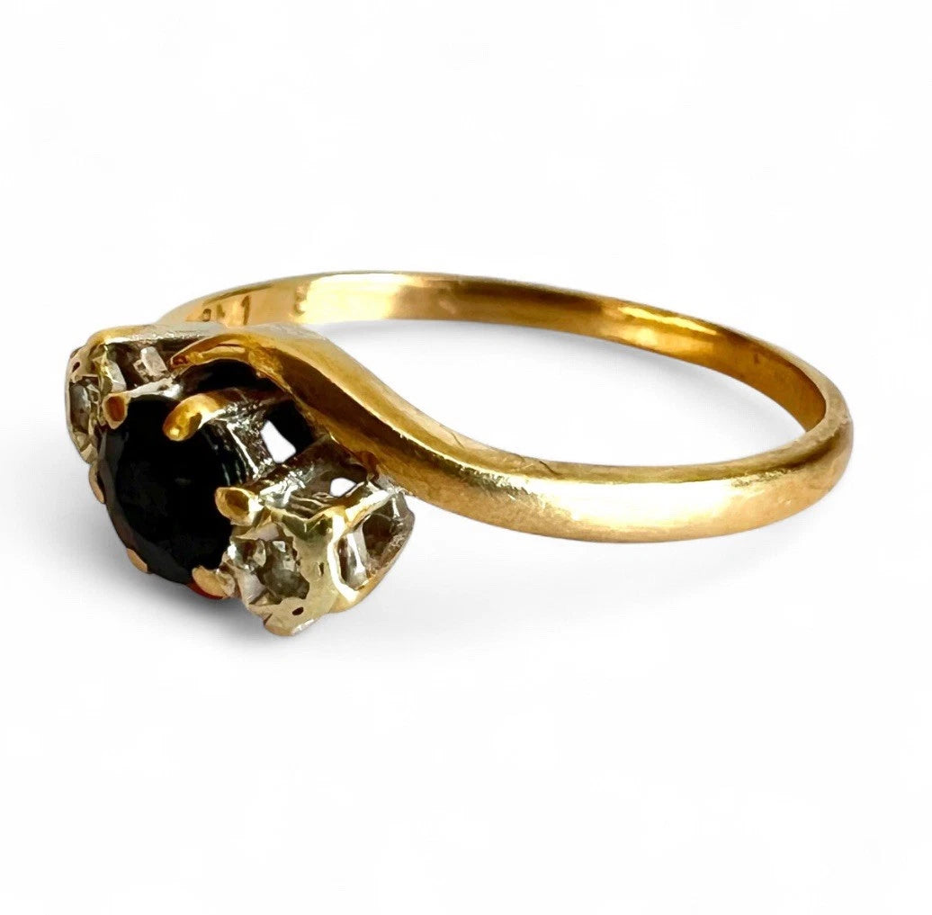 Gold ring with sapphire gemstone and diamonds on a white background