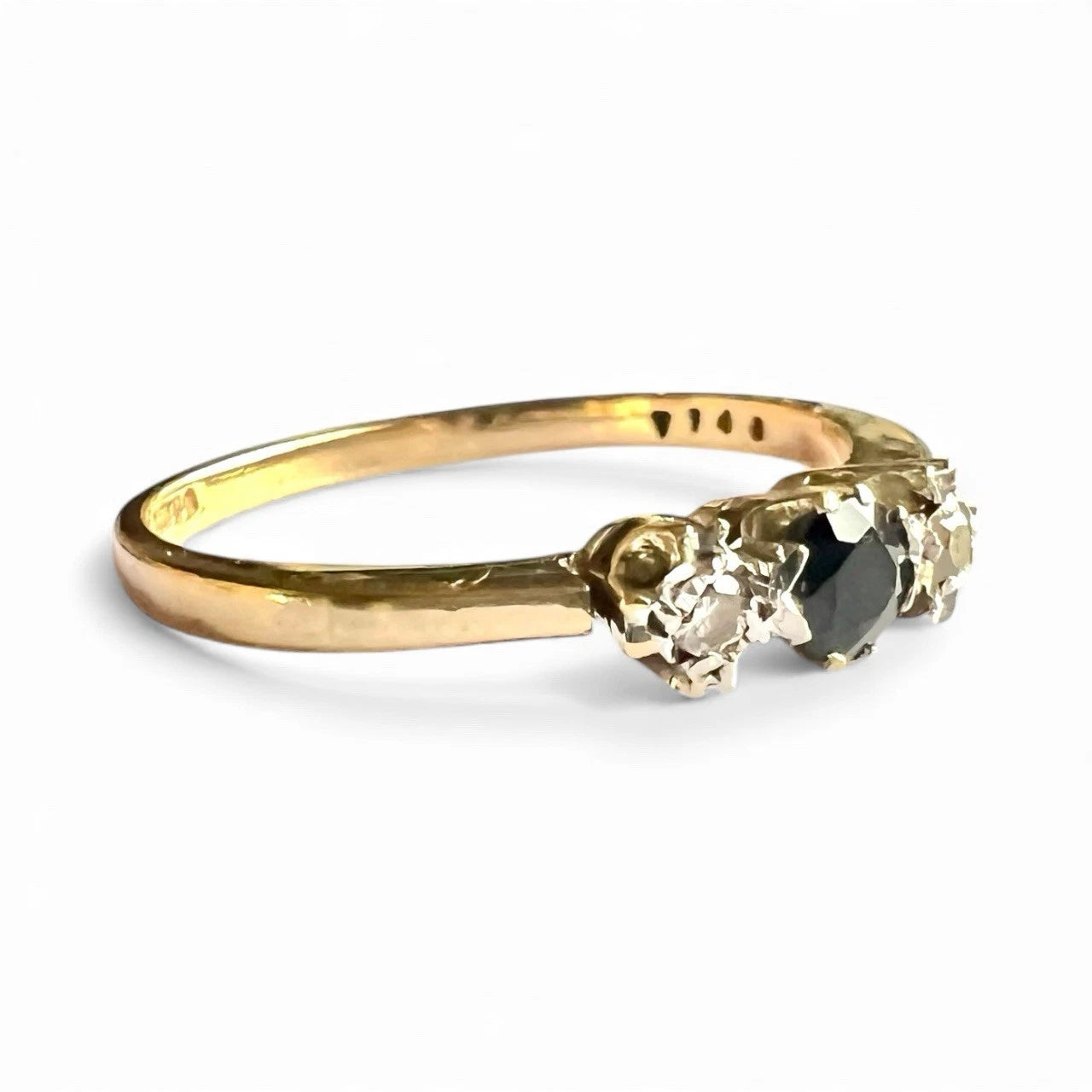 Gold ring with sapphire flanked by two diamonds on a white background