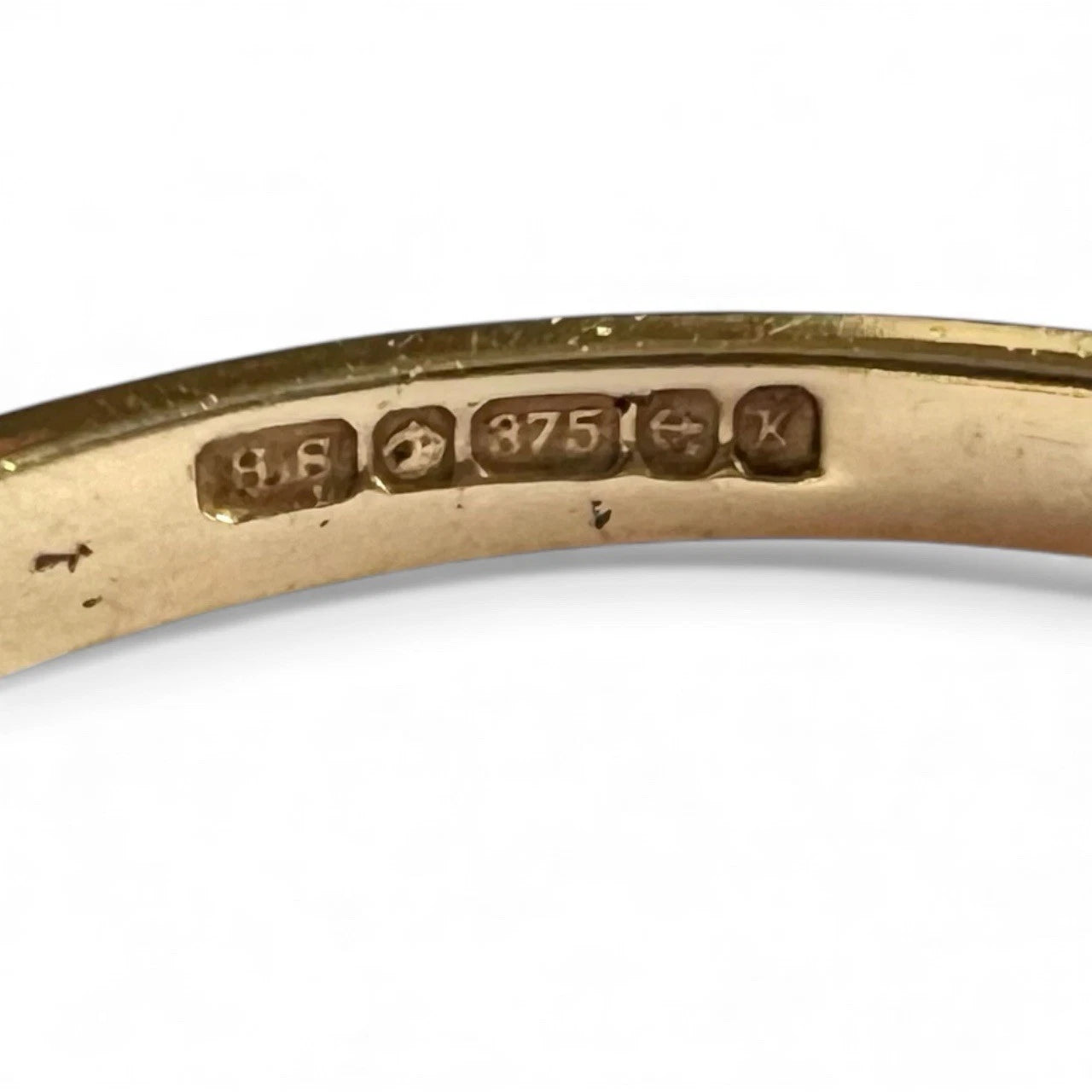 Gold ring with engraved hallmarks on a white background