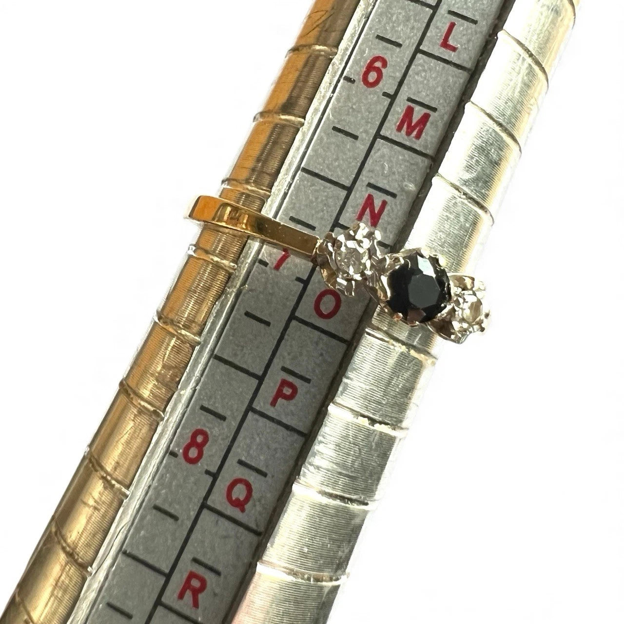 Gold ring with sapphire and diamond on a ruler for size reference