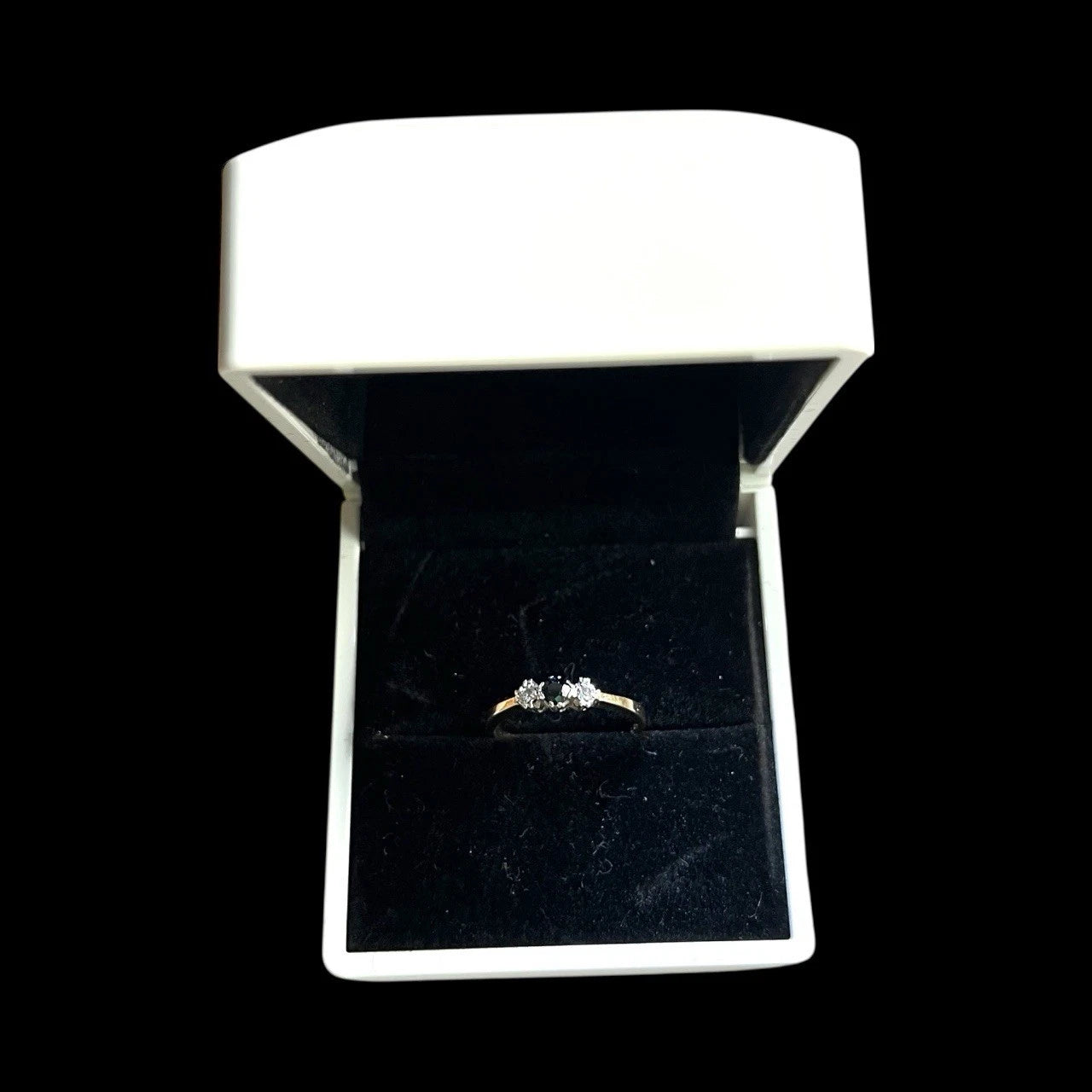 Sapphire and diamond ring in an open jewellery box on a black background