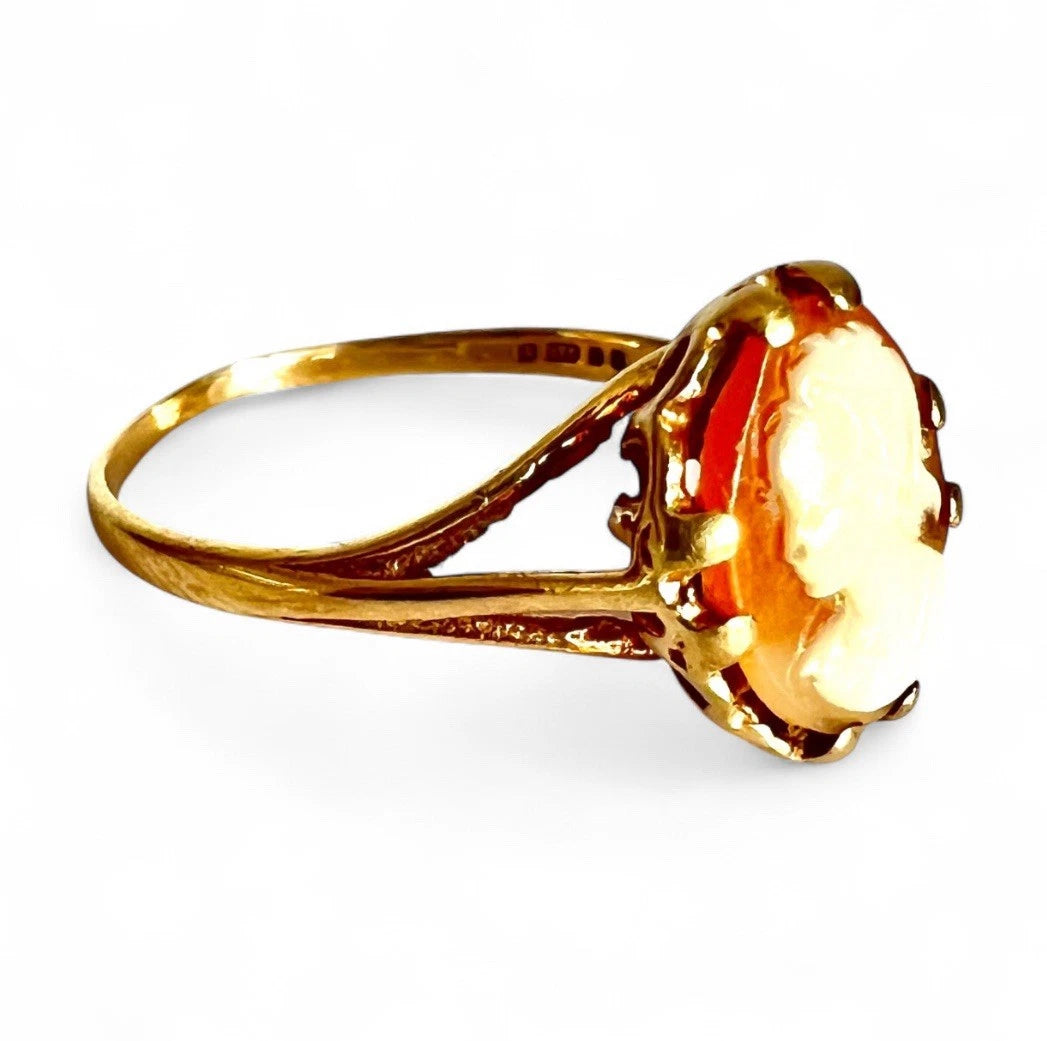 Gold ring with a cameo design on a white background