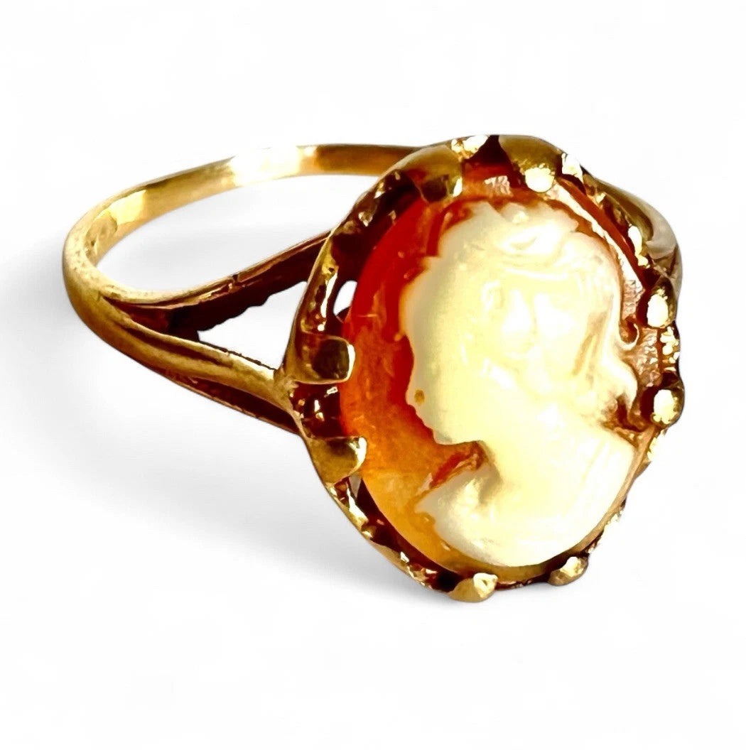Gold ring with a cameo design on a white background