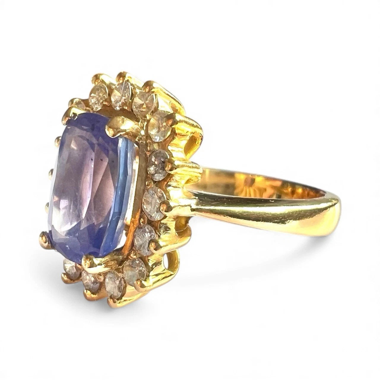 Gold ring with a blue tanzanite gemstone and small diamonds on a white background