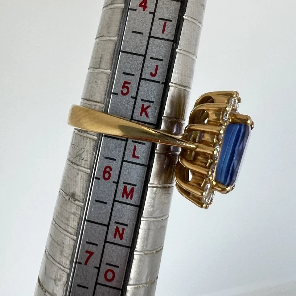 Gold ring with a blue tanzanite gemstone on a metal ruler for size reference
