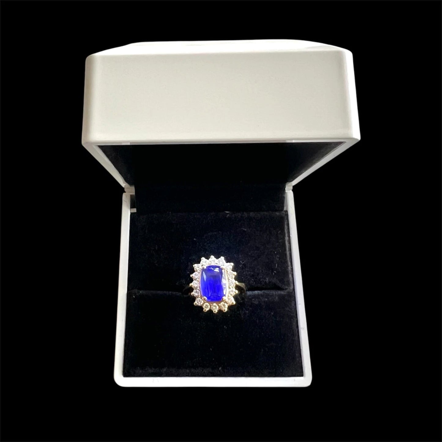 Ring with a blue tanzanite gemstone and diamonds in a white box on a black background