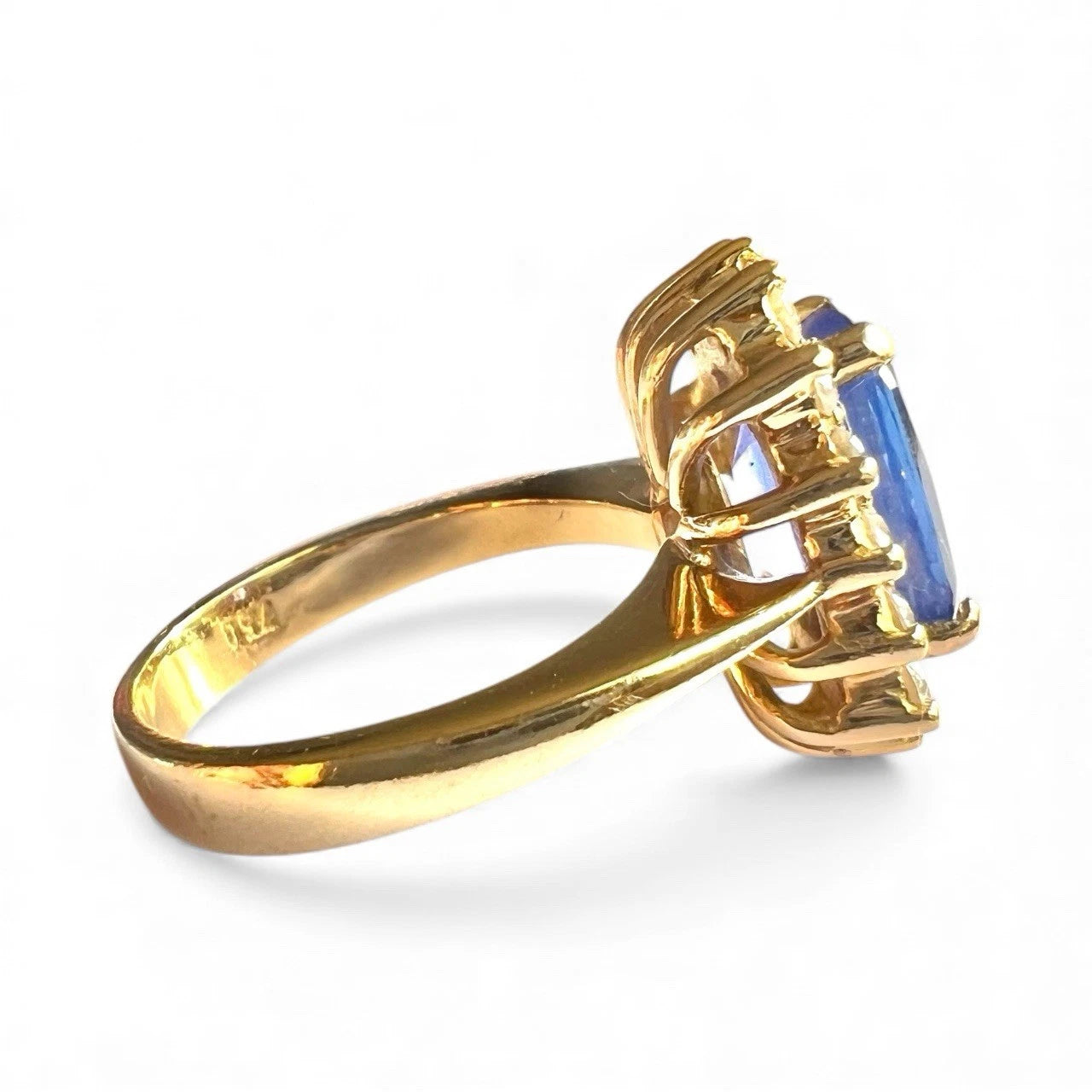 Close-up side view of Gold ring with a blue gemstone on a white background