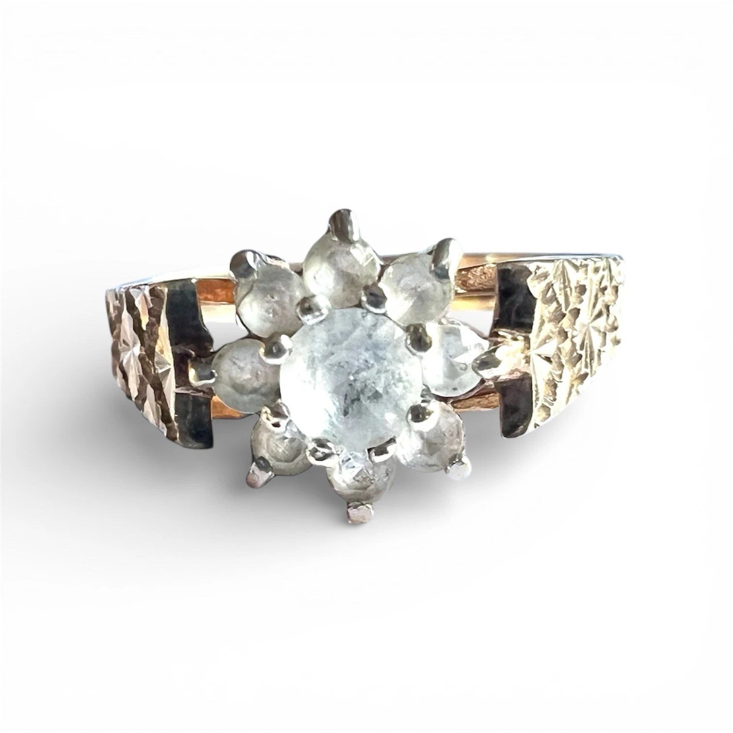 Gold  ring with a topaz gemstones in a flower cluster and textured gold band on a white background