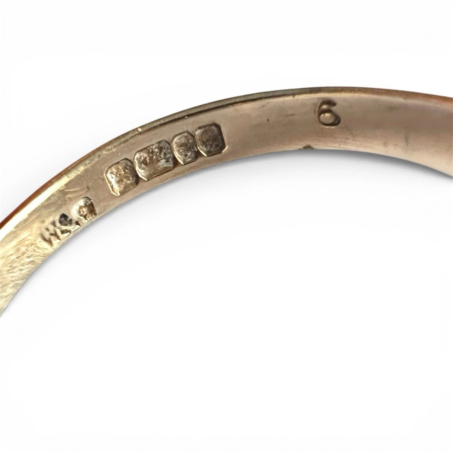 Close-up of a gold ring with engraved hallmark on a white background
