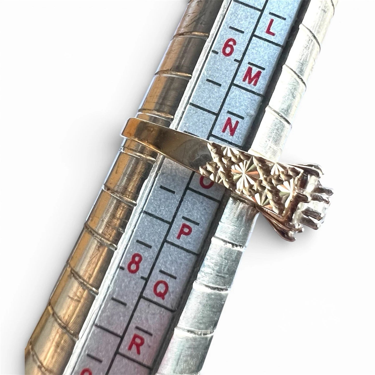 Close-up of a measuring gauge with gold topaz cluster ring on a white background