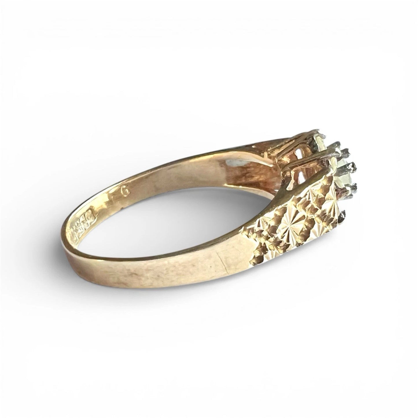Gold ring with a ice blue topaz on a white background, side close up view of engraved detail on band 