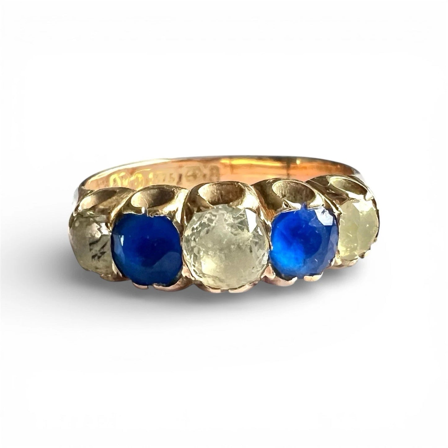 Antique Gold ring with blue and clear gemstones on a white background, close up front view of setting 